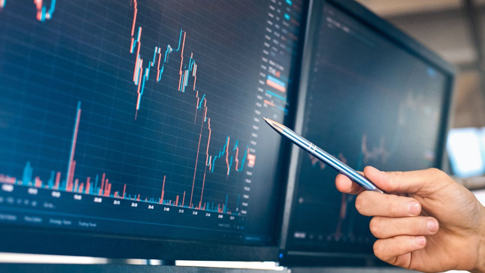 a hand holding a pencil pointing at a Forex market graph