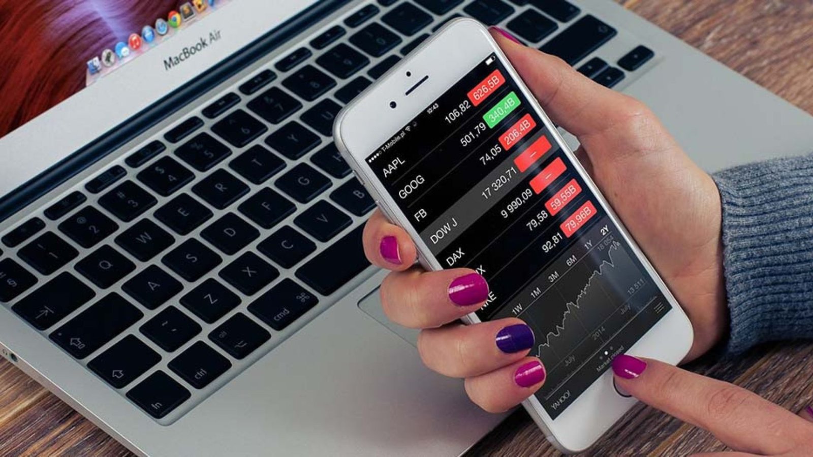 a lady's hand holding a phone showing mobile stock trading
